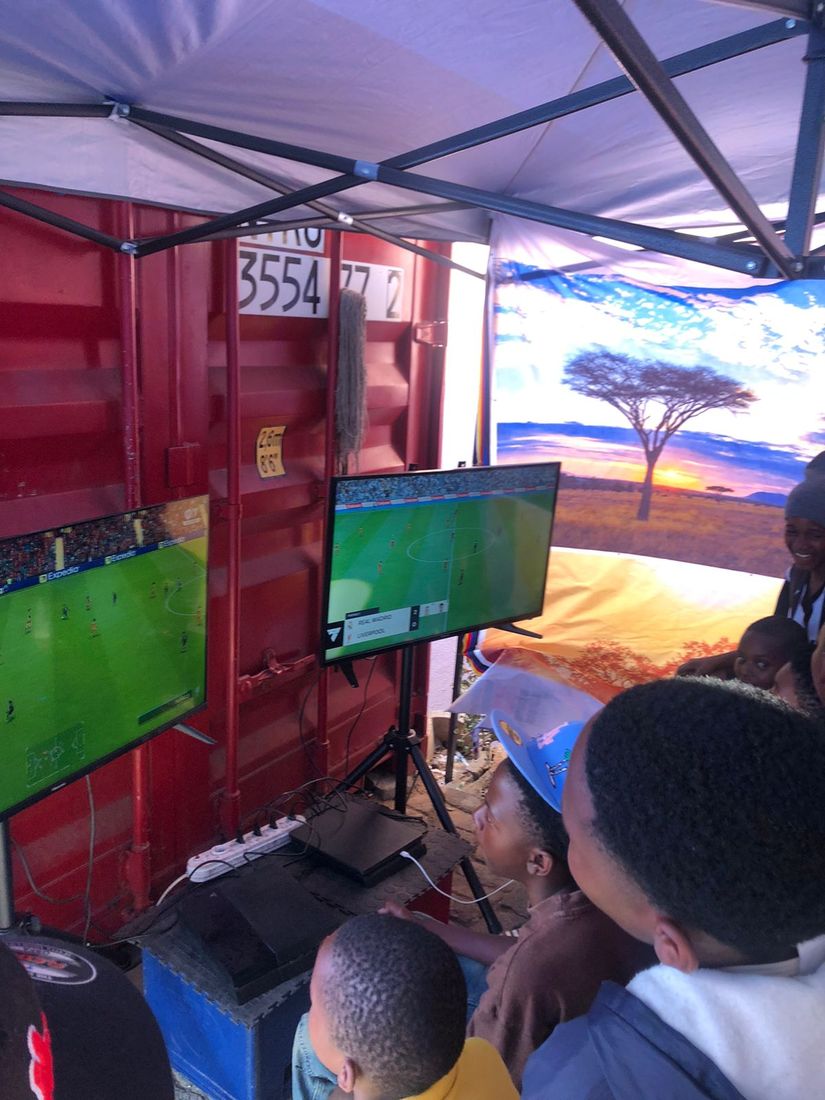 Pop-up gaming setup under a gazebo against a red container