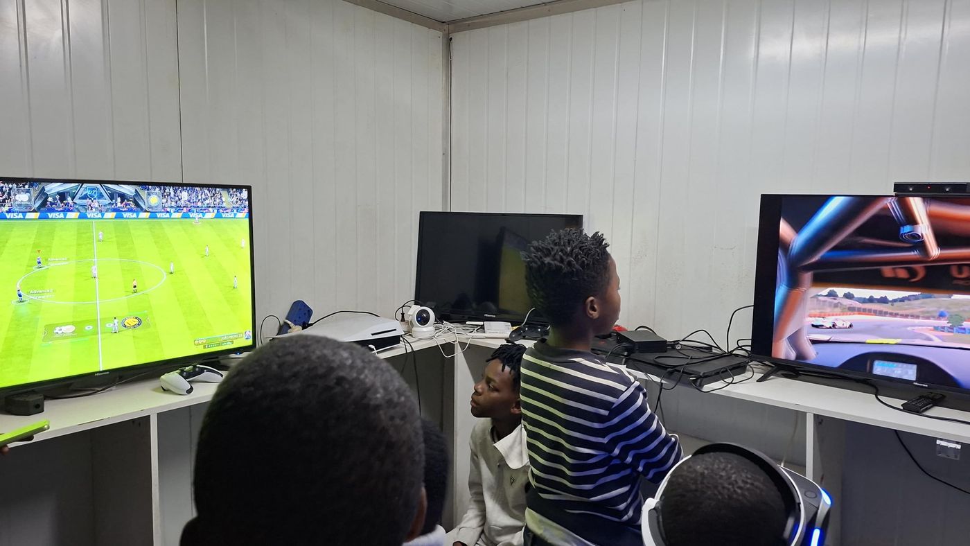 Football on one screen, racing on the other, players crowding around